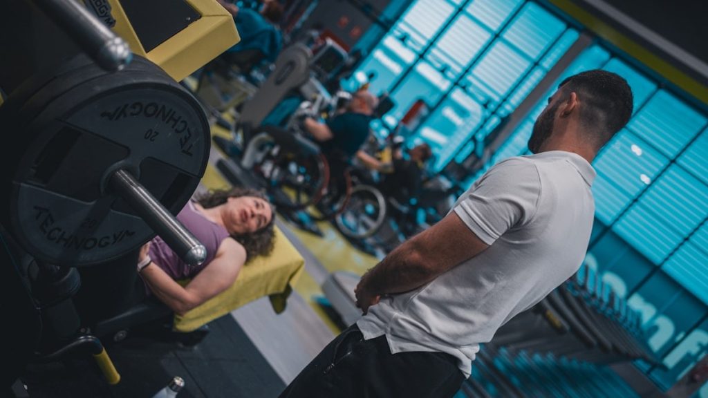 Sesión de entrenamiento en el gimnasio con un entrenador personal, enfocada en el rendimiento y el bienestar físico.
